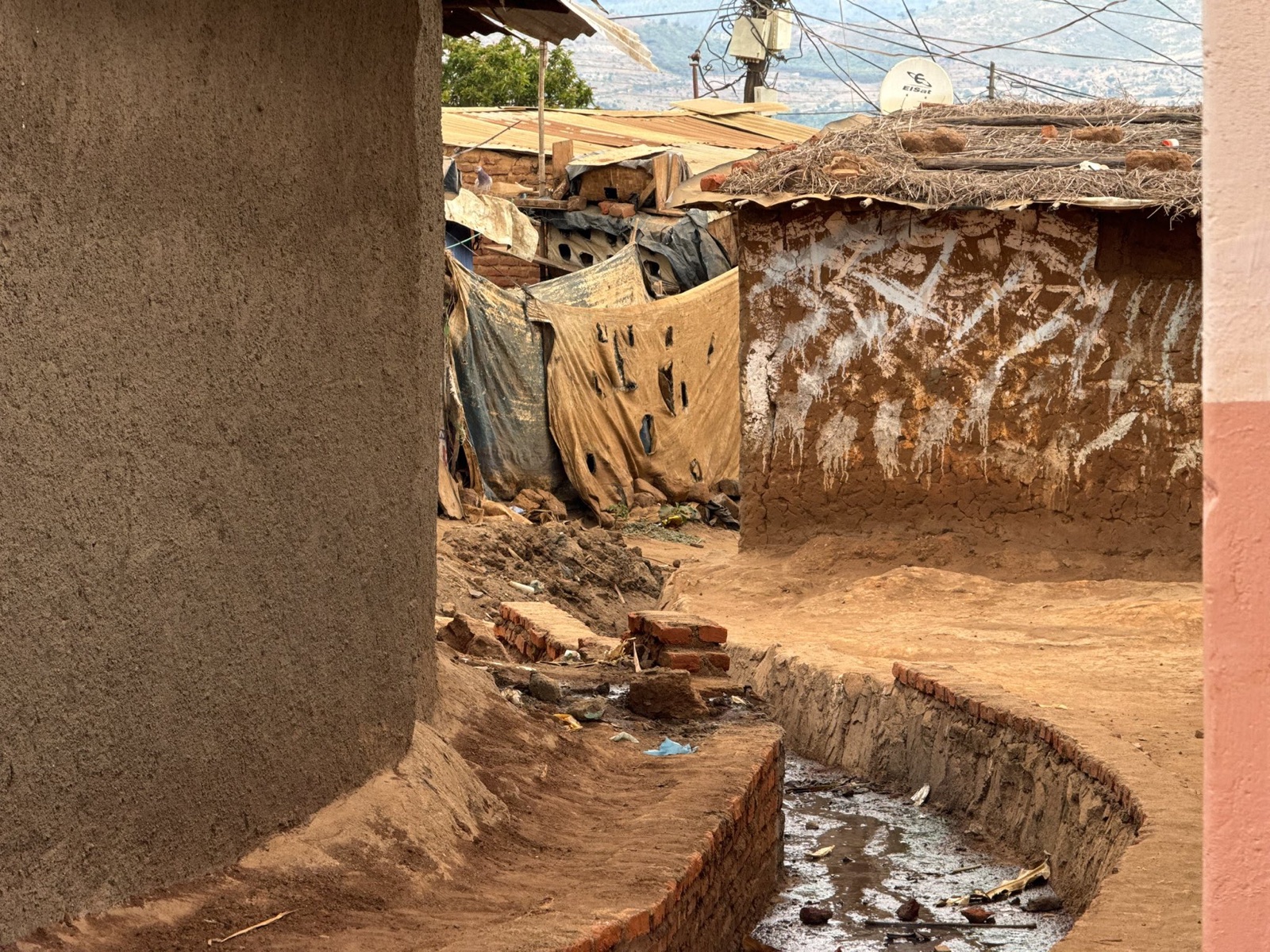 An open drainage channel between homes in Dzaleka