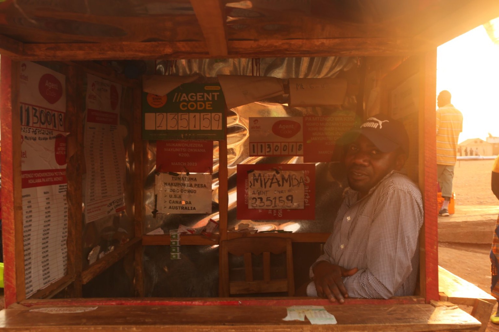 A mobile-money agent sitting inside a kiosk