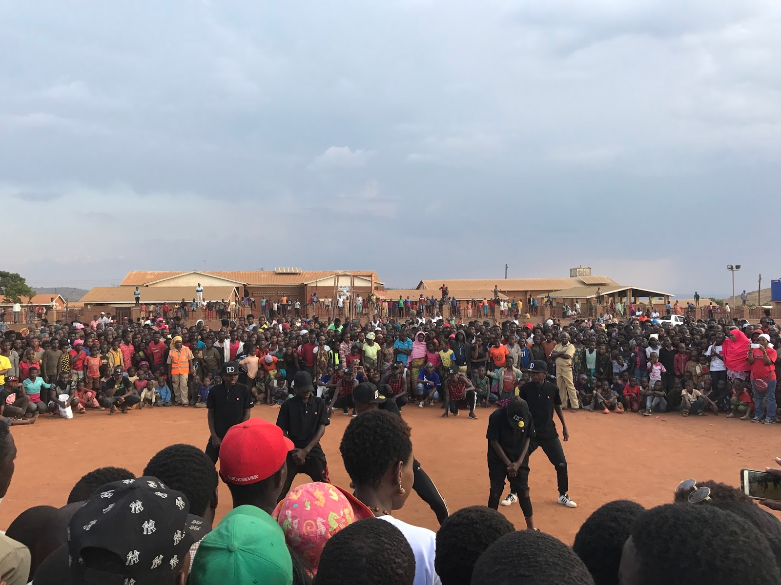 A dance circle forms in the middle of the crowd, with spectators stacked several rows deep.
